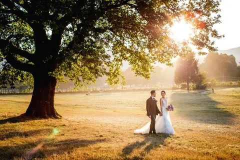 La sposa Erika e lo sposo Luca sotto un grande albero al tramonto.