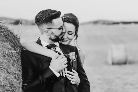 La sposa Erika e lo sposo Luca abbracciati accanto a un fieno.