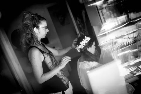 La sposa Federica con un velo e fiori in testa, mentre un'amica le regola l'acconciatura.