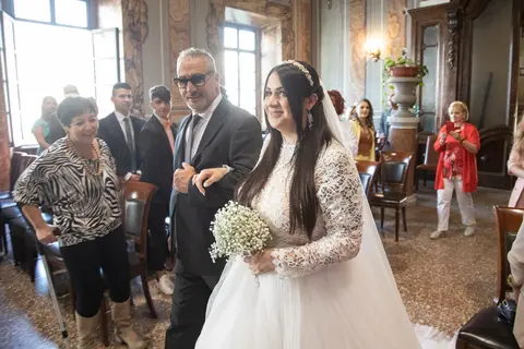 nuziale in abito bianco con velo, tiene un bouquet di gypsophila e cammina con nuziale in un salone decorato.