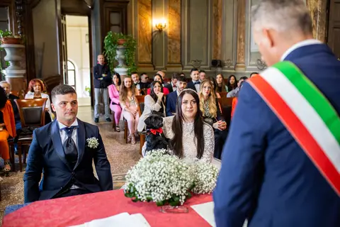 La sposa Silvia e lo sposo Geraldo seduti durante la cerimonia con un cane.