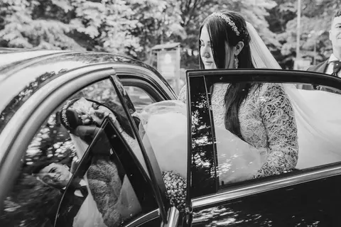 La sposa Silvia esce da un'auto nera in un'immagine in bianco e nero.