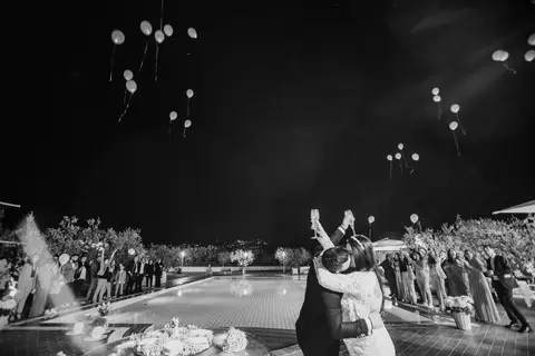 Gli sposi Silvia e Geraldo abbracciati, sollevano i calici mentre i palloncini volano via.