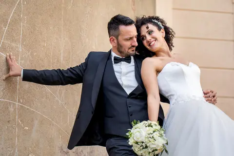 La sposa Giulia e lo sposo Mario si abbracciano contro un muro.