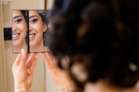 La sposa controlla il trucco in un piccolo specchio a due ante
