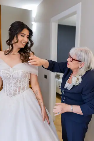La mamma aiuta la sposa a sistemare il corpetto dell'abito