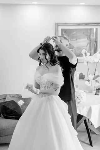 La sposa si sistema il velo aiutata dal papà, in bianco e nero