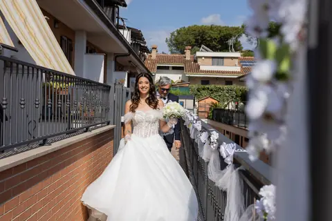 La sposa scende la scala esterna decorata con fiori bianchi