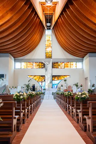 La navata della chiesa con soffitto in legno e composizioni floreali lungo il corridoio