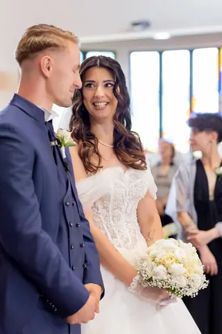 Gli sposi si guardano vicini, la sposa con il bouquet di fiori bianchi