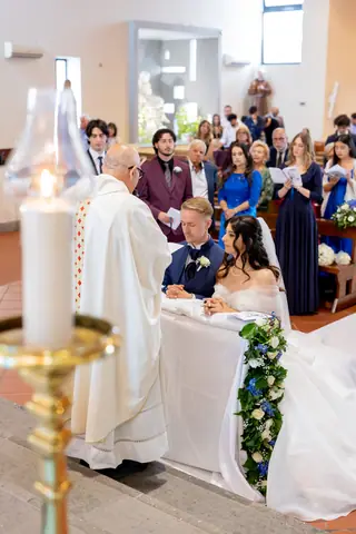 Il celebrante benedice gli sposi inginocchiati durante la messa