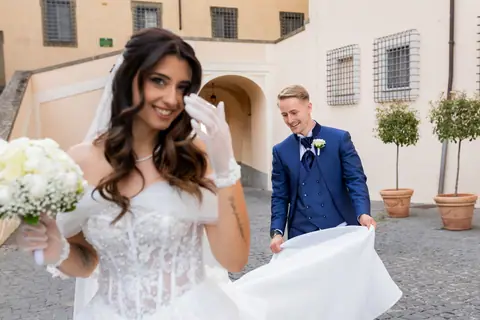 Gli sposi in una piazza del borgo, la sposa sorride verso l'obiettivo