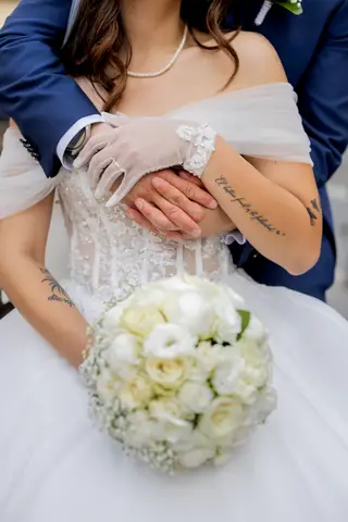 Le mani dello sposo intorno alla vita della sposa che tiene il bouquet