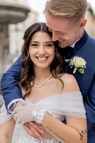 La sposa sorride tra le braccia dello sposo davanti alla fontana