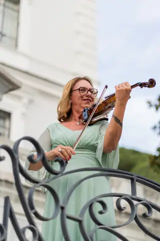 Una violinista in abito verde suona all'aperto durante l'aperitivo