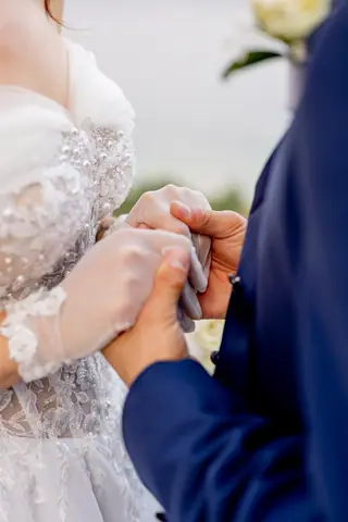 Le mani degli sposi intrecciate, con i guanti di pizzo