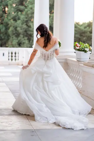 La sposa fa girare la gonna dell'abito sul porticato della villa