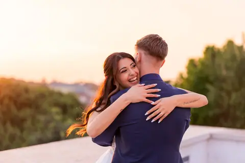 La sposa ride abbracciata allo sposo con la campagna alle spalle