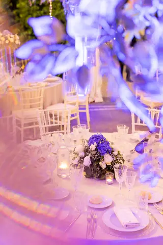 Centrotavola con fiori scuri e candele sotto le luci viola