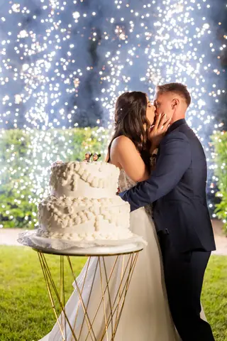 Gli sposi si baciano davanti alla torta nuziale illuminata