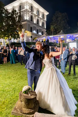 La sposa lancia il bouquet in giardino davanti alla villa illuminata