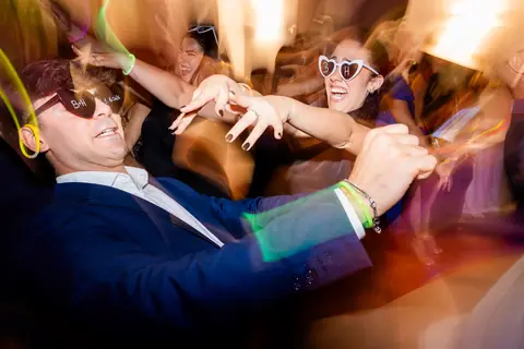 Invitati che ballano mano nella mano nella pista illuminata