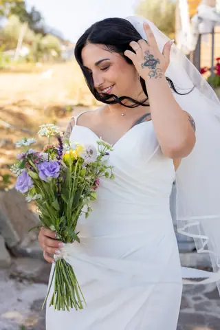 La sposa sistema i capelli con il bouquet in mano