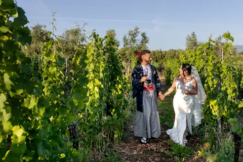 Gli sposi camminano tra le vigne con un calice in mano