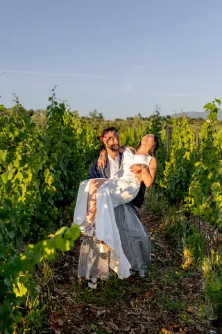 Lo sposo solleva la sposa tra i filari