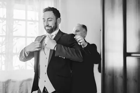 Il testimone sistema la giacca allo sposo, bianco e nero