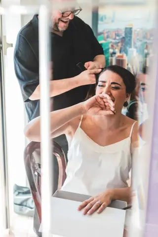 Il parrucchiere sistema l'acconciatura della sposa