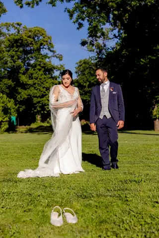 Gli sposi nel parco con le scarpe della sposa in primo piano