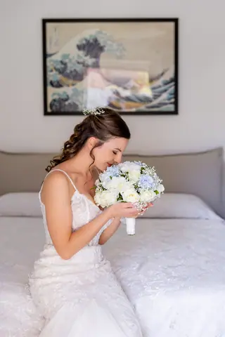 La sposa annusa il bouquet seduta sul letto