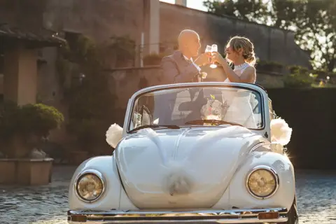 Gli sposi brindano a bordo dell'auto d'epoca