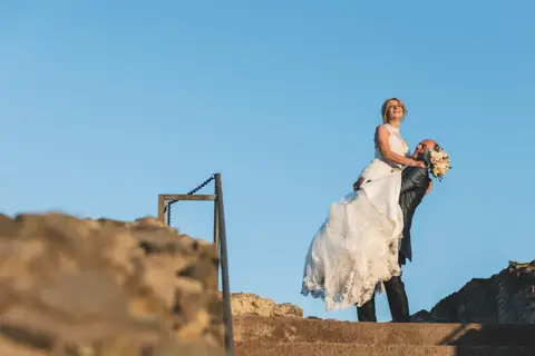 La sposa sollevata dallo sposo sopra le rovine