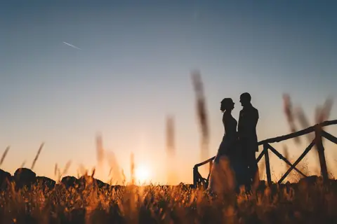 Le silhouette degli sposi al tramonto tra le spighe