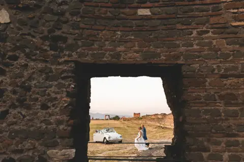 L'auto d'epoca e gli sposi inquadrati attraverso una finestra antica