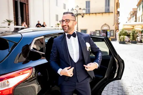 Lo sposo scende dall'auto blu sistemandosi la giacca in piazza