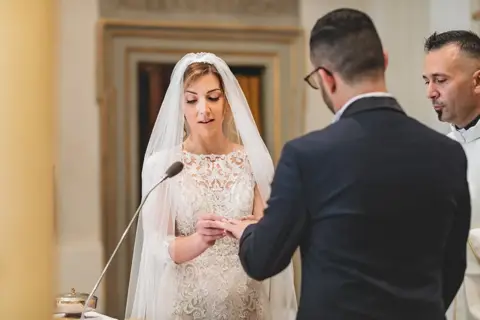 La sposa firma davanti al celebrante e allo sposo