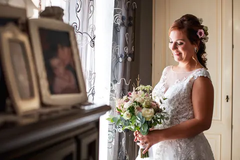 La sposa Michela in abito bianco tiene un bouquet e guarda verso il basso.