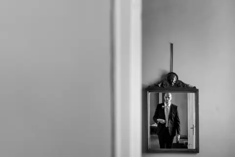Lo sposo Federico in abito da sposo, riflesso in uno specchio.