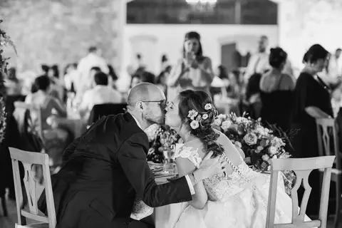 Gli sposi Michela e Federico si baciano a tavola durante il matrimonio.