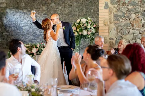 La sposa Michela e lo sposo Federico si baciano mentre gli invitati applaudono.