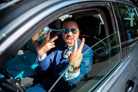 Lo sposo Daniele in auto, con occhiali da sole e gesto di vittoria.