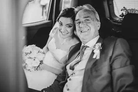 La sposa Veronica e lo sposo Daniele sorridono in auto.
