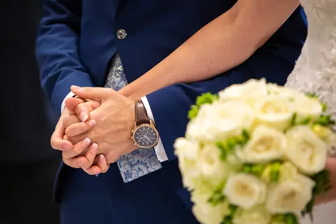 Gli sposi Veronica e Daniele stringono le mani, con il bouquet della sposa in primo piano.
