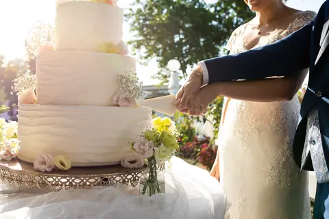 Gli sposi Veronica e Daniele tagliano la torta nuziale all'aperto.